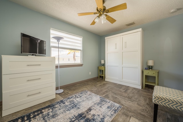 interior space with ceiling fan, dark parquet flooring, and a textured ceiling