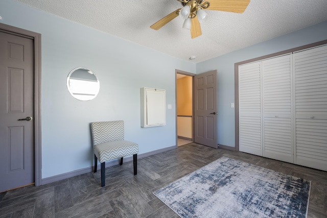 living area with dark parquet flooring, ceiling fan, and a textured ceiling