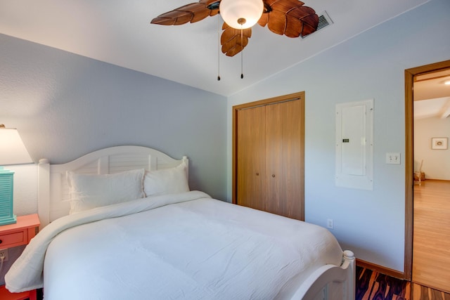 bedroom featuring lofted ceiling, ceiling fan, electric panel, wood-type flooring, and a closet