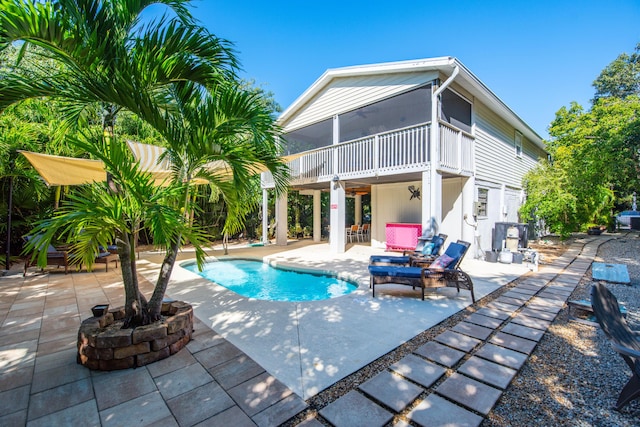 view of swimming pool with a sunroom and a patio area