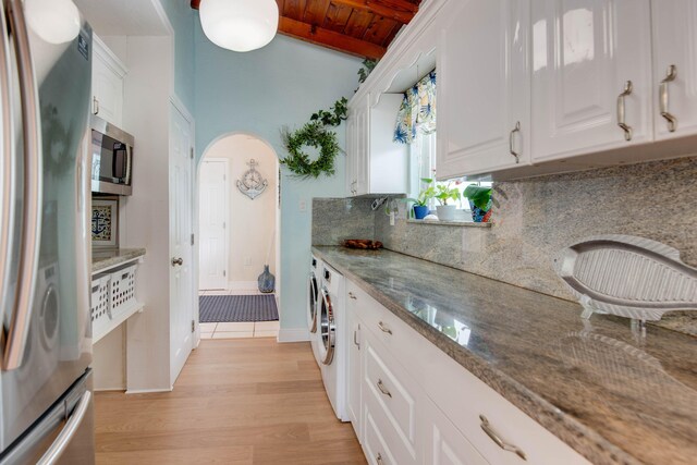 kitchen with white cabinetry, stone countertops, wooden ceiling, stainless steel appliances, and washer and clothes dryer