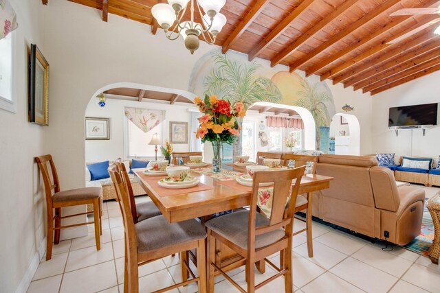 dining area with light tile patterned flooring, vaulted ceiling with beams, an inviting chandelier, and wood ceiling