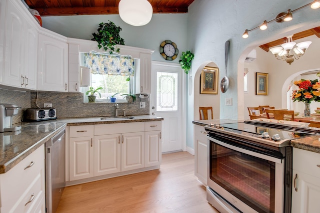 kitchen with sink, white cabinetry, light wood-type flooring, stainless steel appliances, and decorative backsplash