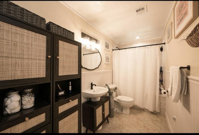 bathroom with toilet, sink, and ornamental molding