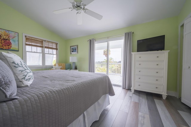 bedroom with multiple windows, light wood-type flooring, access to outside, and vaulted ceiling