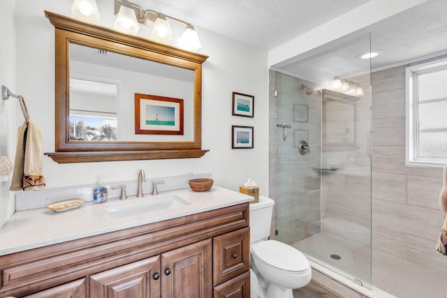 full bathroom with vanity, toilet, and tiled shower