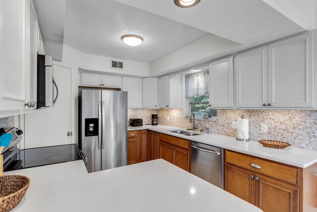 kitchen with visible vents, a sink, stainless steel appliances, light countertops, and decorative backsplash