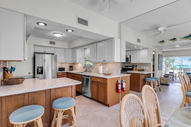 kitchen with visible vents, a peninsula, stainless steel appliances, and a sink