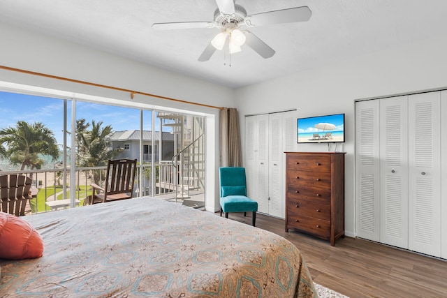 bedroom featuring access to exterior, wood finished floors, two closets, and ceiling fan