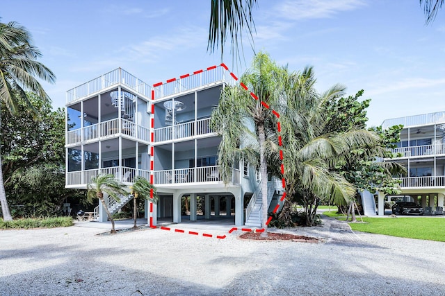 view of building exterior featuring a carport, driveway, and stairs