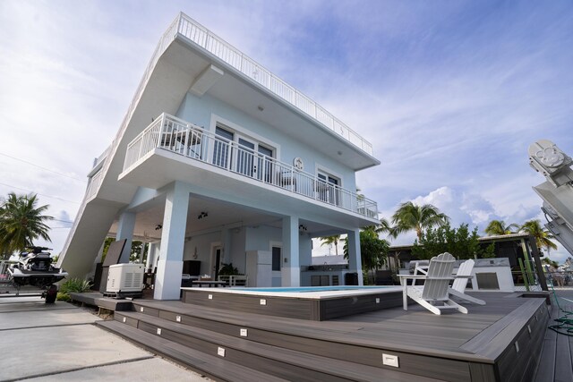 rear view of house with a swimming pool, a patio area, and a balcony