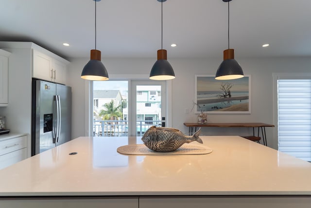 kitchen featuring stainless steel refrigerator with ice dispenser, decorative light fixtures, a center island, and white cabinets