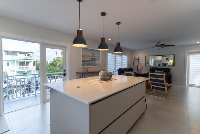 kitchen with decorative light fixtures, a center island, light tile patterned floors, ceiling fan, and white cabinets