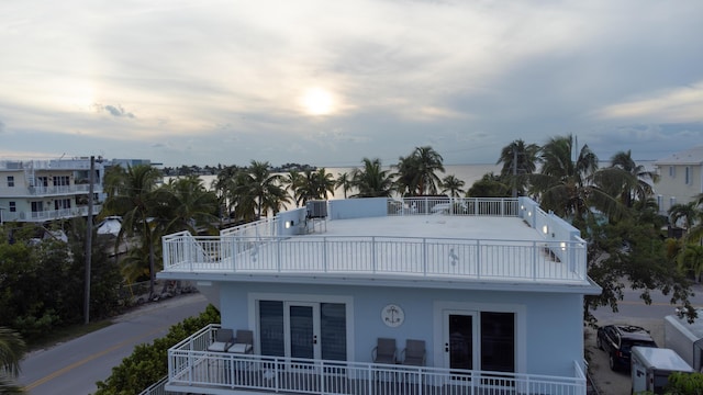 back house at dusk featuring french doors and a balcony