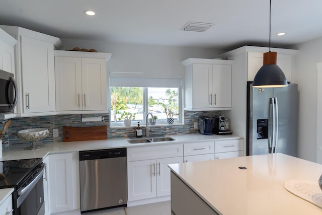 kitchen featuring sink, hanging light fixtures, appliances with stainless steel finishes, white cabinets, and backsplash