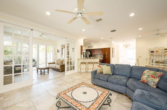 living room with ornamental molding, ceiling fan with notable chandelier, light tile patterned floors, and french doors