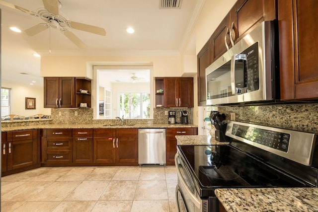 kitchen with light stone counters, sink, ornamental molding, and appliances with stainless steel finishes