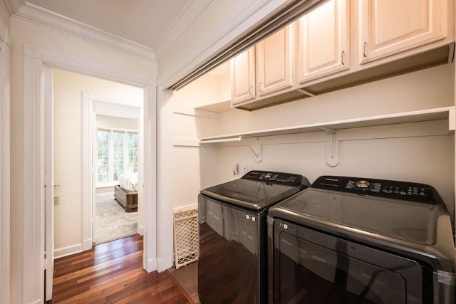 laundry area featuring dark wood-type flooring, ornamental molding, cabinets, and washing machine and clothes dryer