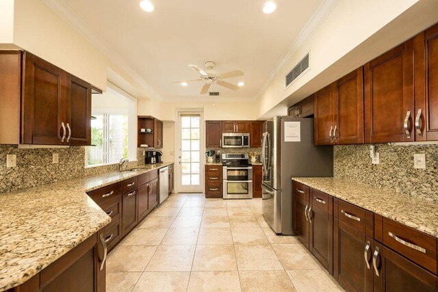 kitchen featuring light stone counters, stainless steel appliances, crown molding, and sink