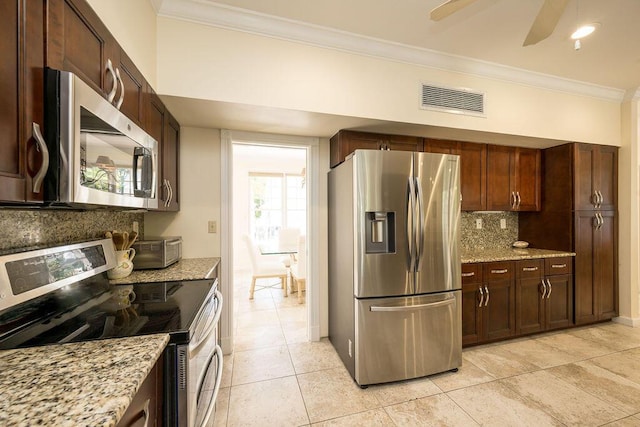 kitchen featuring crown molding, appliances with stainless steel finishes, tasteful backsplash, light stone countertops, and light tile patterned flooring