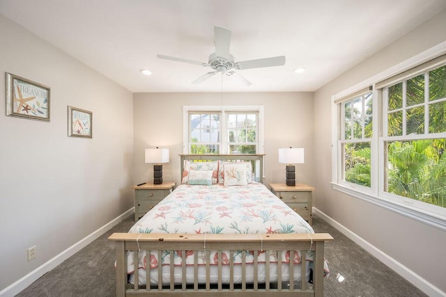 bedroom with ceiling fan, dark carpet, and multiple windows