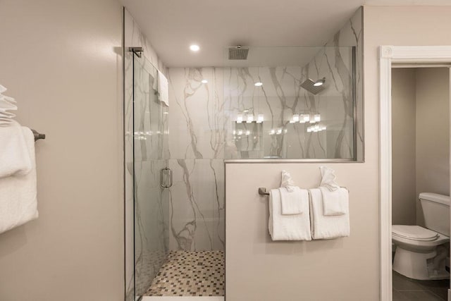 bathroom featuring a shower with shower door and toilet