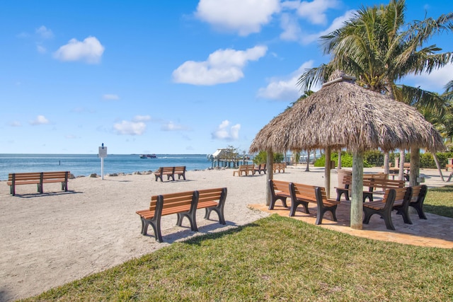 view of community featuring a gazebo, a lawn, a beach view, and a water view