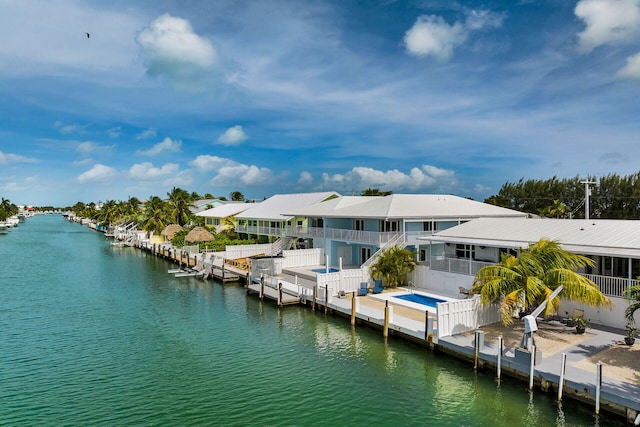 dock area featuring a water view, a balcony, and a swimming pool