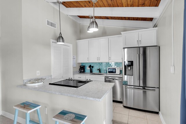 kitchen featuring appliances with stainless steel finishes, white cabinets, hanging light fixtures, light tile patterned floors, and kitchen peninsula