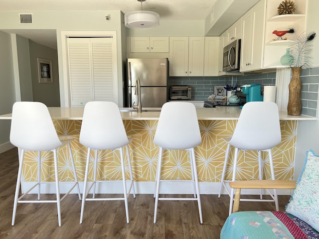 kitchen with wood finished floors, a toaster, open shelves, appliances with stainless steel finishes, and visible vents