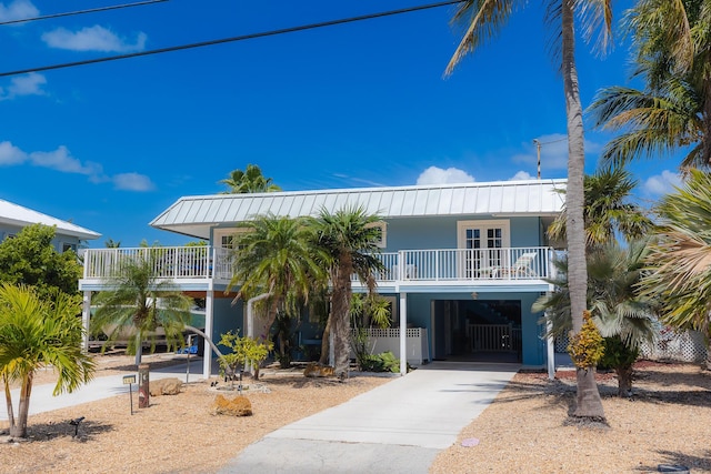 beach home with stucco siding, a carport, metal roof, and concrete driveway