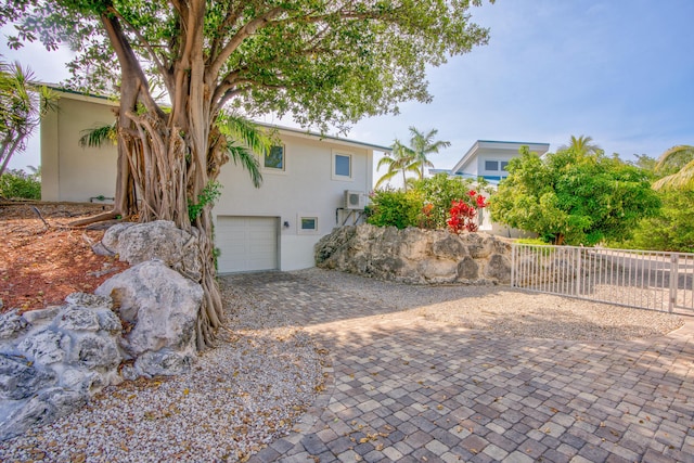 view of side of property featuring a garage and a wall mounted AC