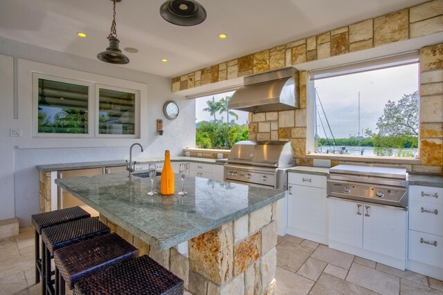 kitchen with range hood, a kitchen breakfast bar, white cabinets, and a center island with sink