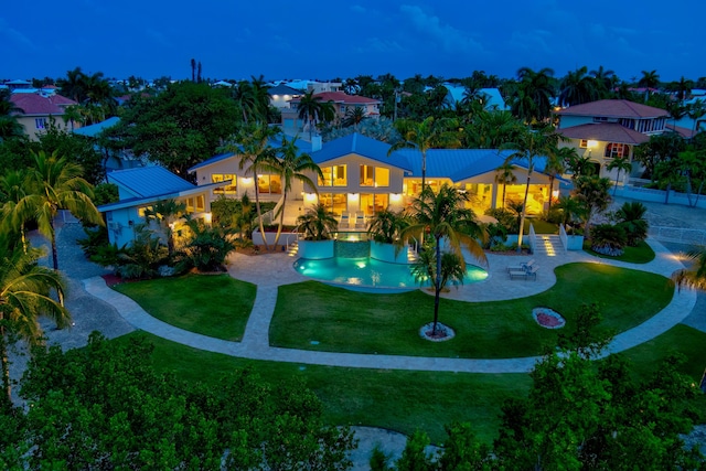 pool at twilight featuring a lawn and a patio area