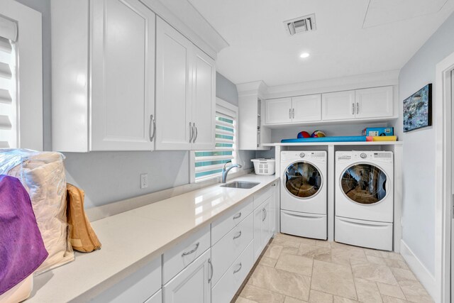 clothes washing area featuring cabinets, sink, and independent washer and dryer