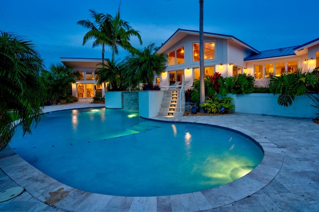 pool at dusk with a patio area