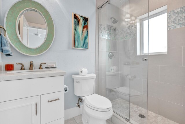 bathroom featuring vanity, a shower with shower door, tile patterned floors, and toilet