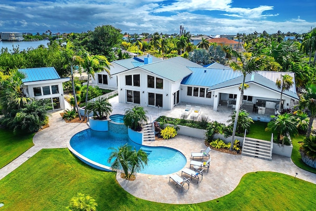 view of pool featuring a hot tub, a water view, a lawn, and a patio area