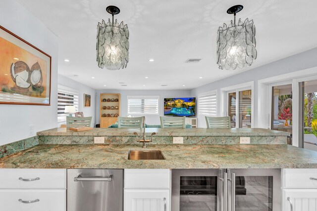 kitchen featuring white cabinetry, sink, and hanging light fixtures