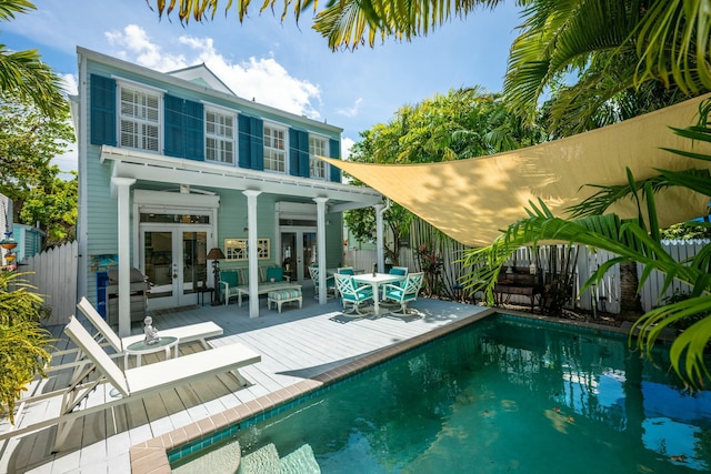 rear view of house featuring a pool side deck and french doors