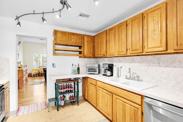 kitchen featuring backsplash, dishwasher, sink, and light wood-type flooring