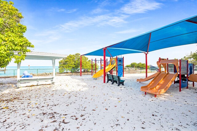 view of jungle gym featuring a water view and a view of the beach