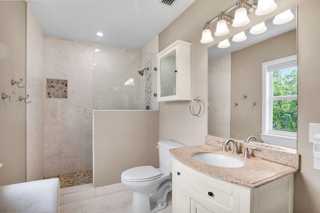 bathroom with tiled shower, vanity, toilet, and tile patterned floors