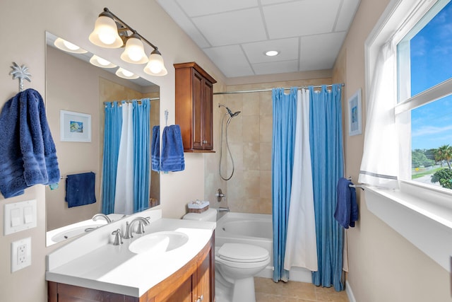 full bathroom with tile patterned floors, toilet, vanity, shower / bath combo with shower curtain, and a drop ceiling