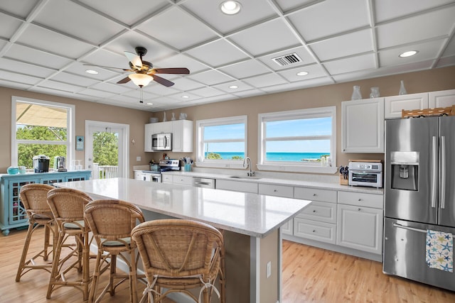 kitchen with sink, a center island, stainless steel appliances, light stone countertops, and white cabinets