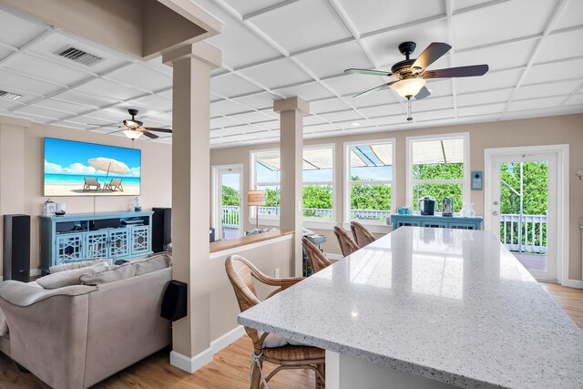 living room featuring a paneled ceiling, light hardwood / wood-style floors, decorative columns, and a healthy amount of sunlight