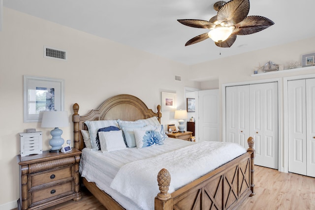 bedroom featuring ceiling fan, two closets, and light hardwood / wood-style floors