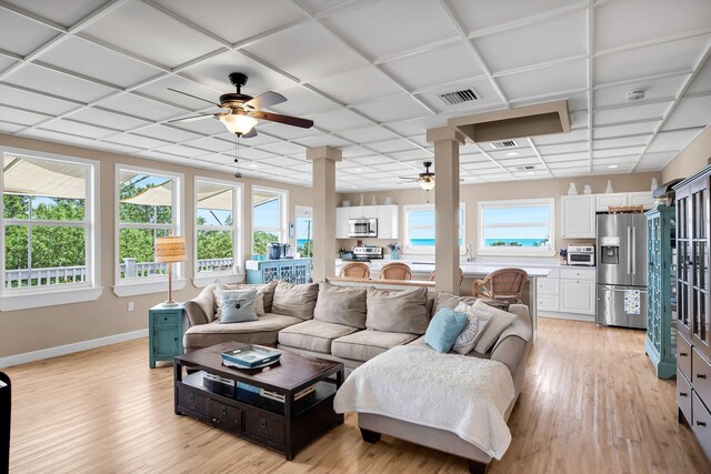 living room with ceiling fan, a paneled ceiling, a healthy amount of sunlight, and light wood-type flooring