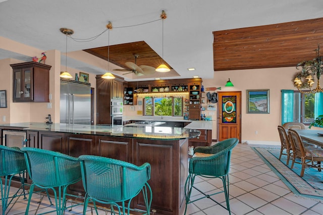 kitchen with dark brown cabinetry, light tile patterned floors, wooden ceiling, a peninsula, and stainless steel appliances