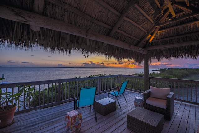 deck at dusk featuring a water view